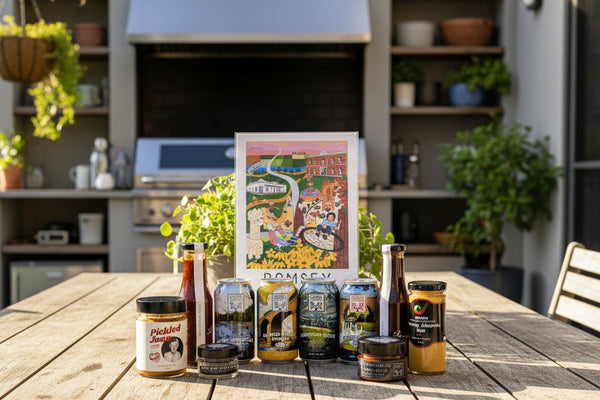 the contents of a craft beer and bbq condiments hamper including sauces from Beth Shan, Emelia's, Chintin Botanicals and Pickled Joan. All from the Macedon Ranges. This version includes an A4 art print from Elise Gow Designs.