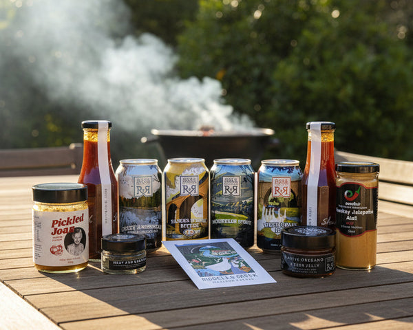 the contents of a craft beer and bbq condiments hamper including sauces from Beth Shan, Emelia's, Chintin Botanicals and Pickled Joan. All from the Macedon Ranges. 
