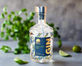 a bottle of dry gin distilled in the Macedon Ranges sitting on kitchen bench with limes and herbs. 