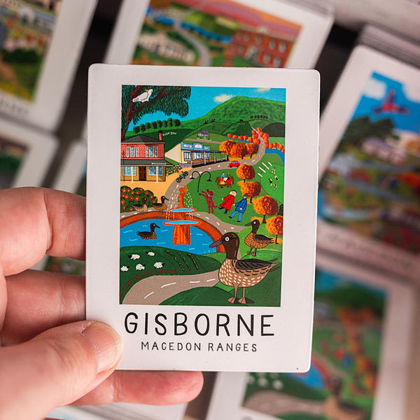 Card with a colorful illustration magnet of Gisborne and Macedon Ranges, held by a hand.