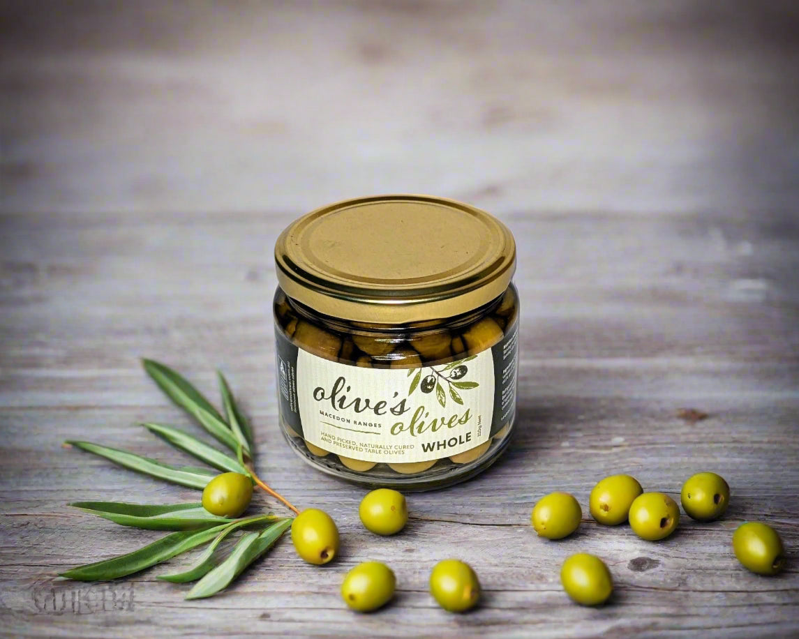 a jar of green table olives grown in the Macedon Ranges on a table with some green olives