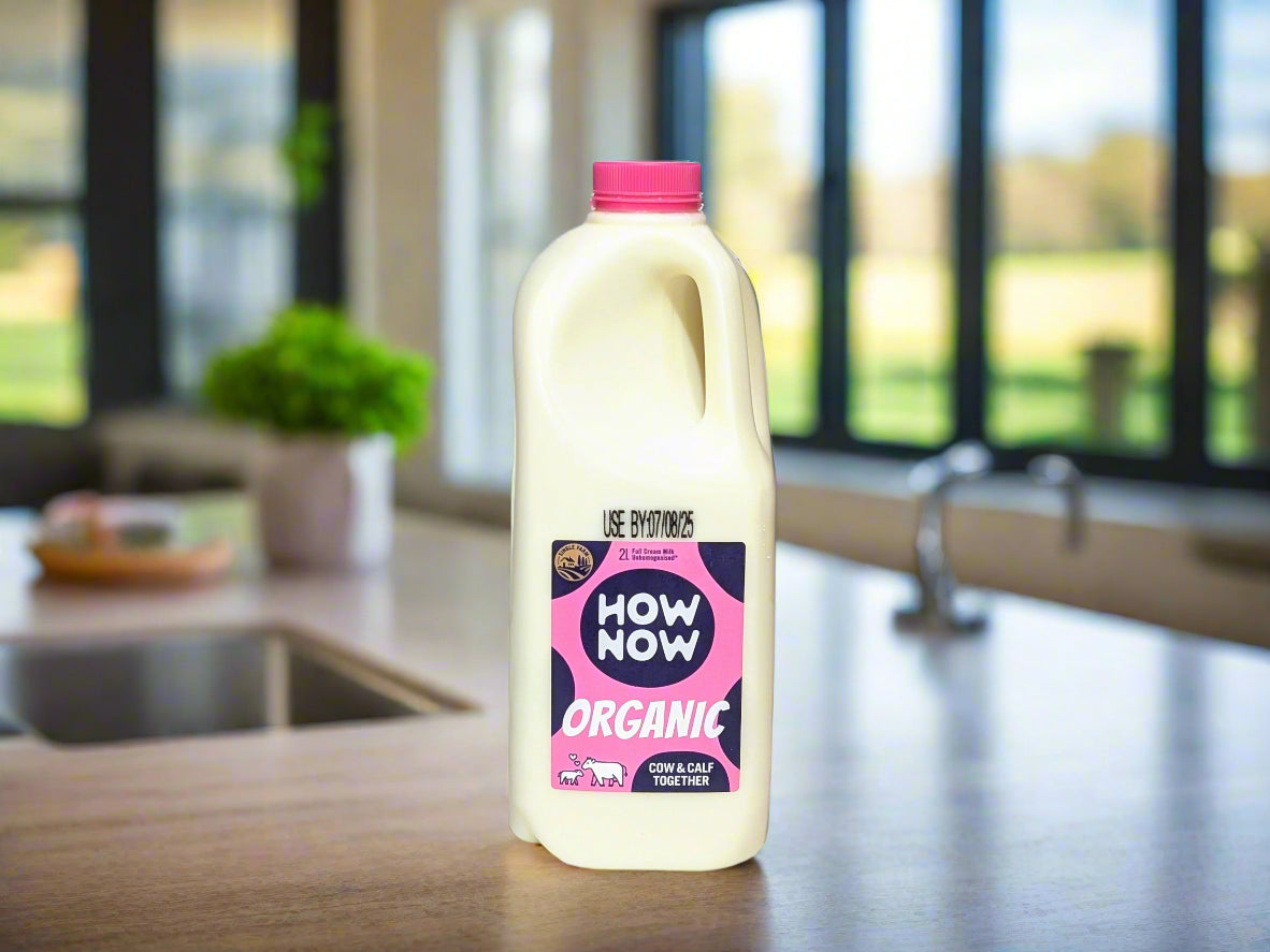 Bottle of How Now Organic milk with a pink cap on a white background
