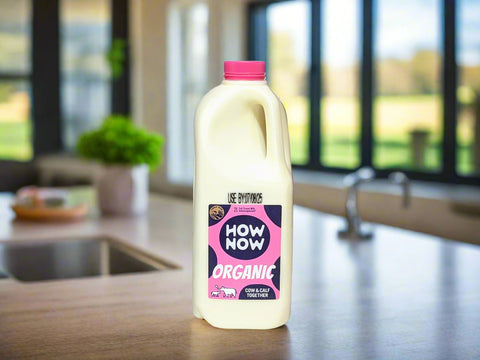 Bottle of How Now Organic milk with a pink cap on a white background