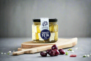 a jar of marinated feta from the Macedon Ranges on serving board with olives